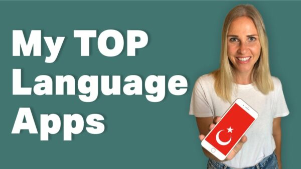 A person smiling holds a smartphone displaying the Turkish flag. Text reads "My TOP Language Apps" on a green background.