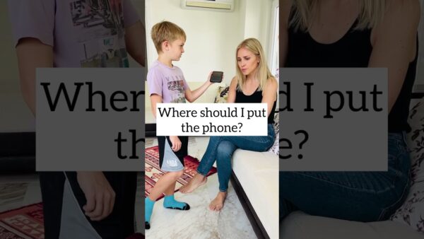 A child holding a phone stands near a seated person on a couch. Text overlay reads, "Where should I put the phone?"
