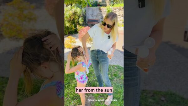 A person applies sunscreen to a child outdoors. They're in a garden with lush greenery and sunlight. A small bench is visible.