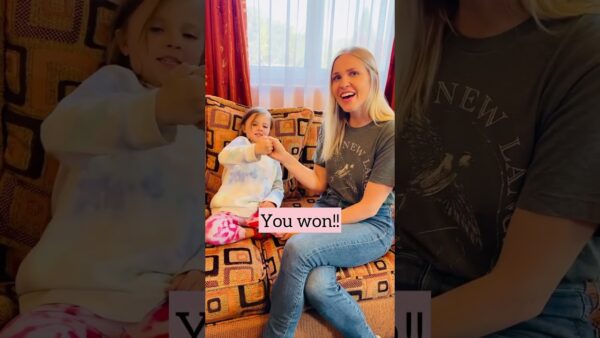 A child and a person sitting on a patterned couch, smiling, with "You won!!" text overlay. Bright curtain in the background.