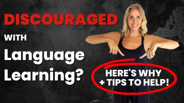 A person points to text offering language learning tips on a black textured background. The text addresses discouragement in language learning.
